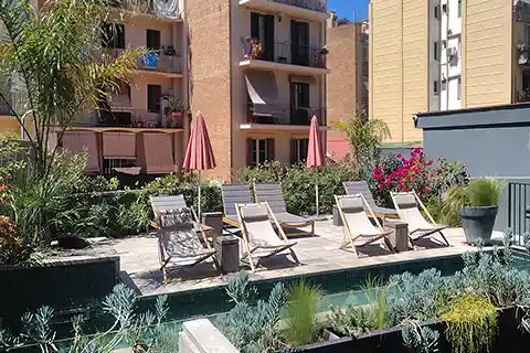Terraza de hotel con tumbonas, piscina y jardineras con plantas